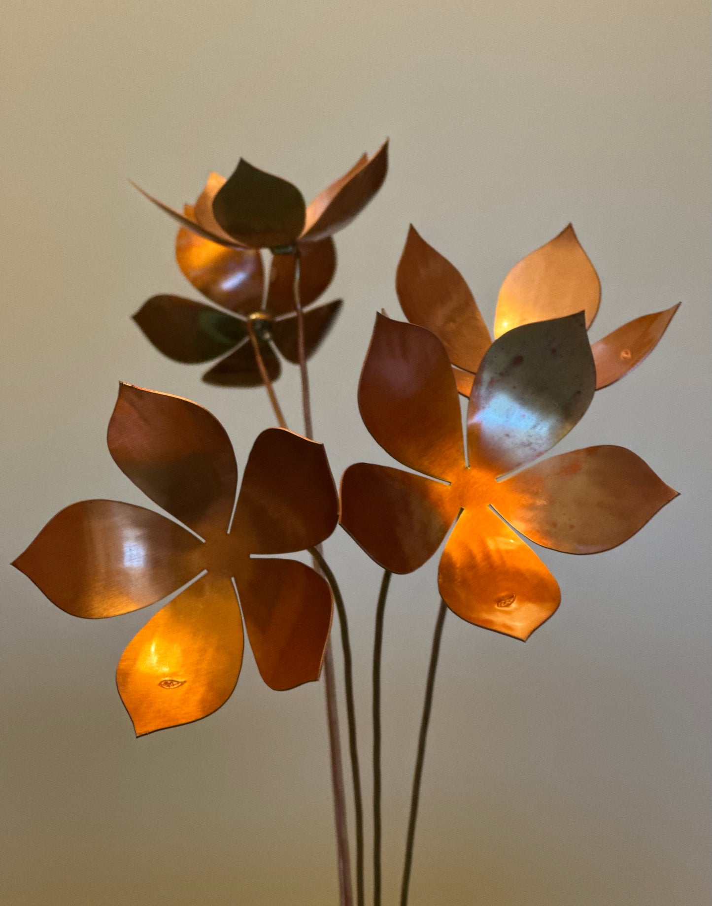 Decorative metal flower sculpture with a warm metallic finish on a plain background